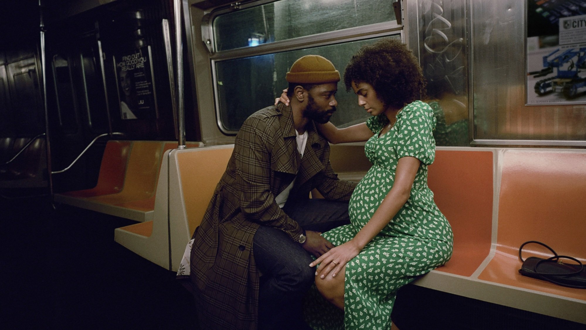 A man and a pregnant woman sitting in a subway car.