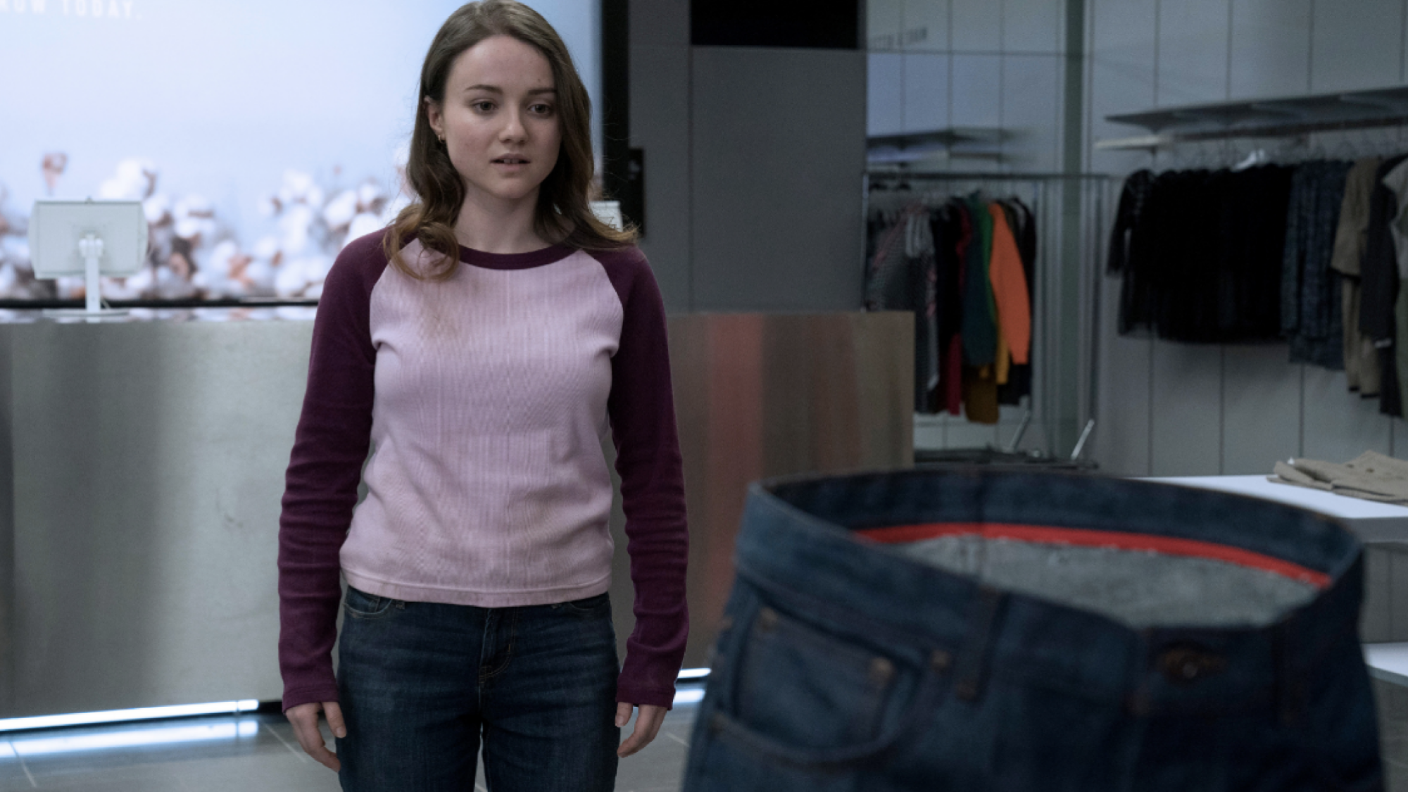 A woman stands staring at a pair of jeans.