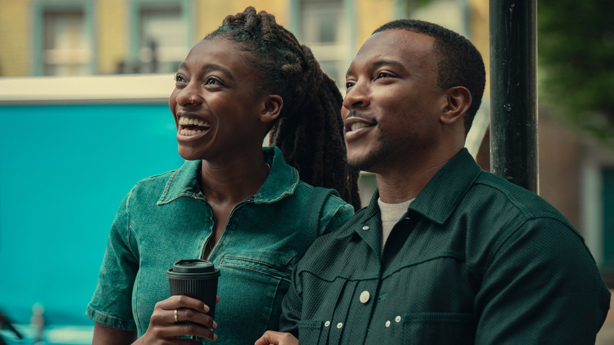 Simbi Ajikawo and Ashley Walters stand arm in arm smiling and holding coffee in the TV show "Top Boy"